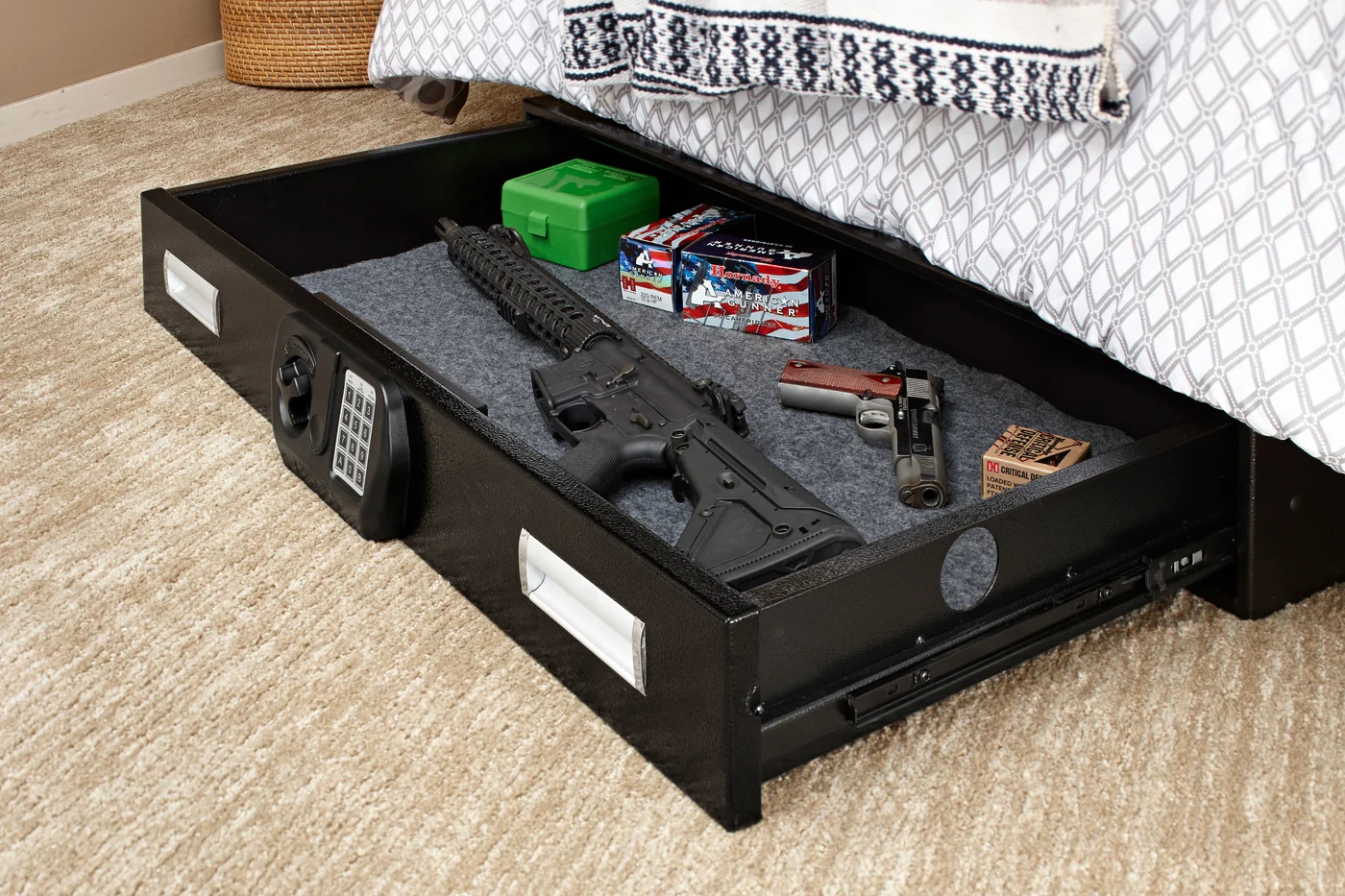A SnapSafe under-bed gun safe drawer slid out from beneath a bed holding a rifle, a pistol and ammunition