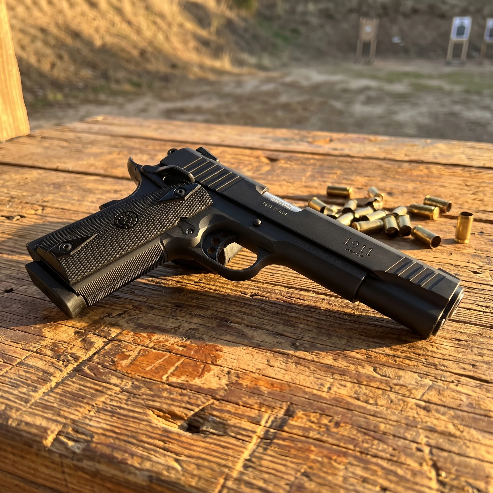 Taurus 1911 resting on a wooden shooting bench at an outdoor range with spent brass beside it