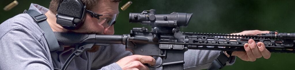 Shooter firing an AR-15 topped with a Trijicon ACOG 3.5x35 LED