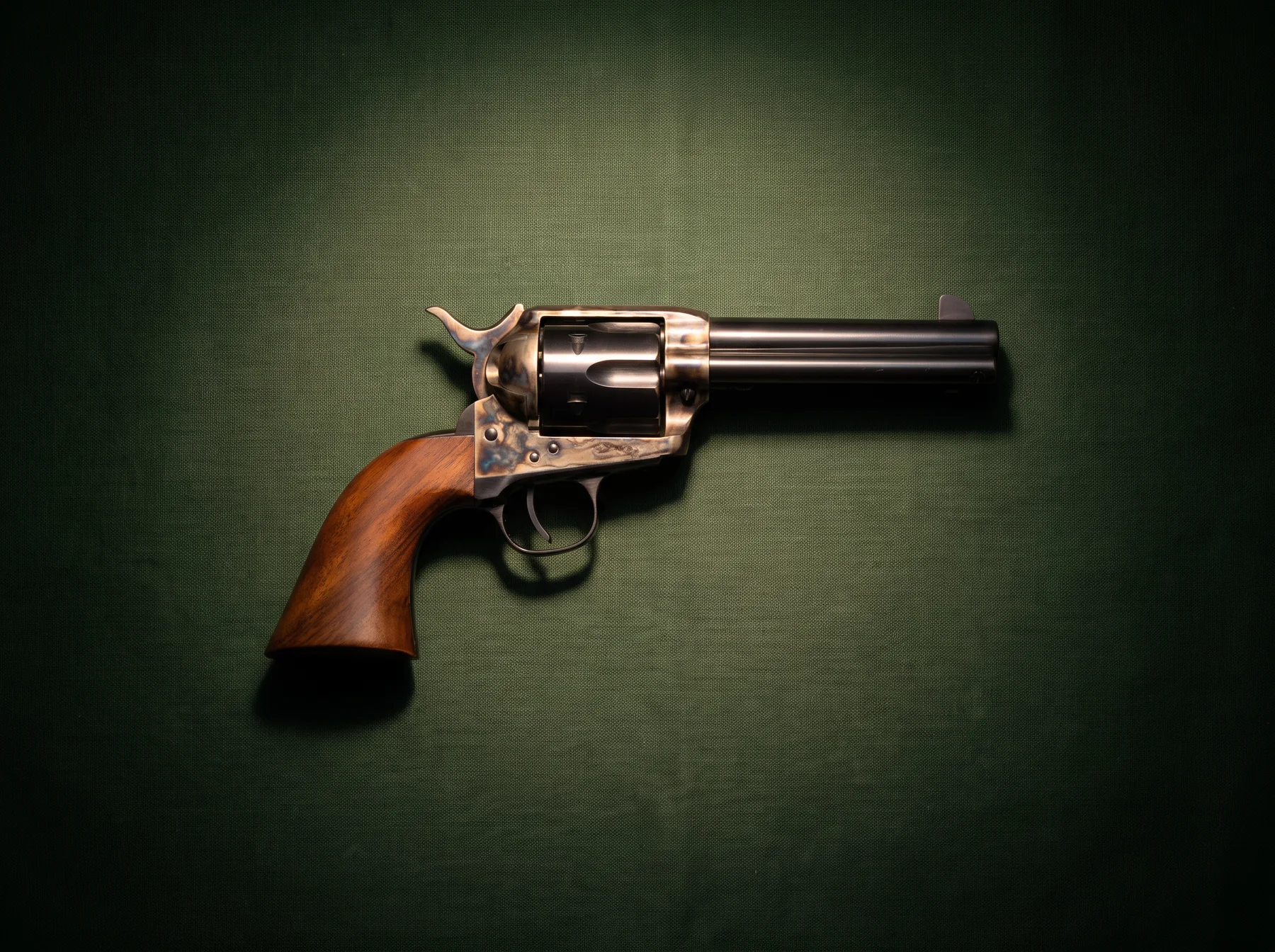 Uberti 1873 Cattleman Steel model with case-hardened frame and walnut grip on dark green canvas, seen from above