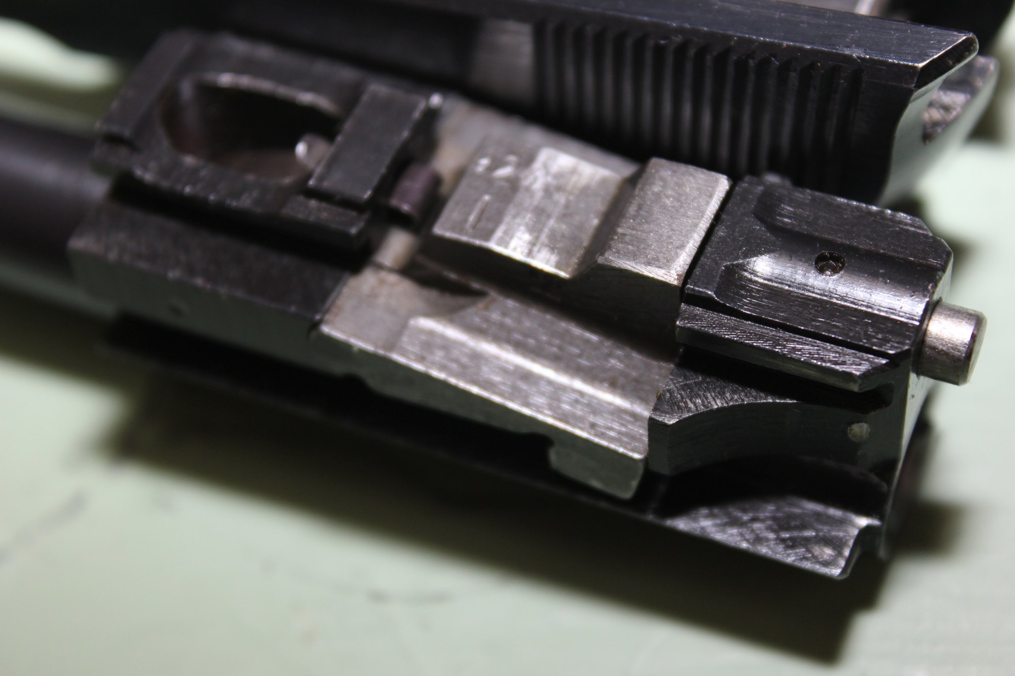 Close-up of a field-stripped Walther P38 barrel showing the pivoting locking block beneath the chamber