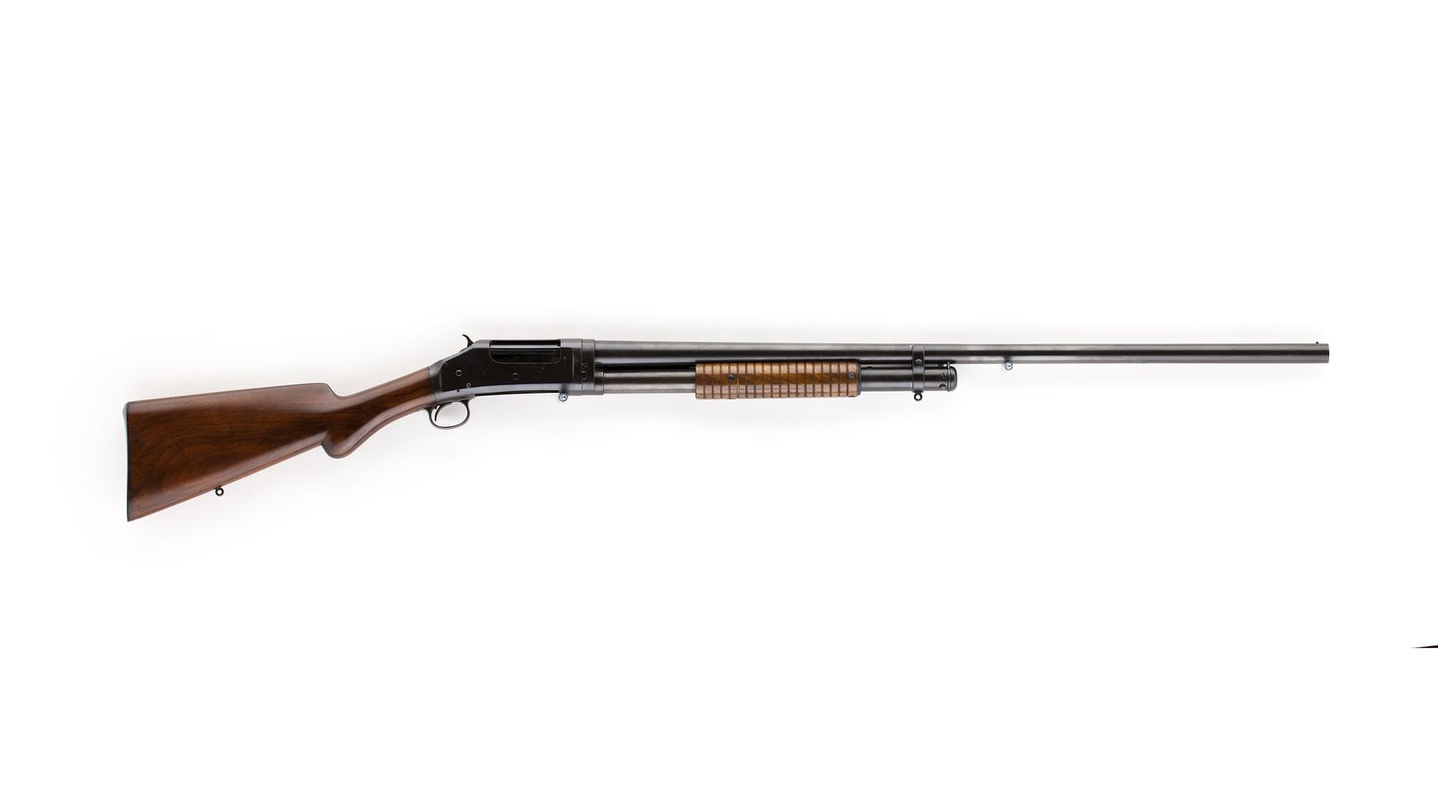 Winchester Model 1897 pump shotgun with exposed hammer, long barrel and walnut stock, right side on a white background