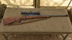 Winchester Model 70 rifle with a scope on a canvas table in a military training tent