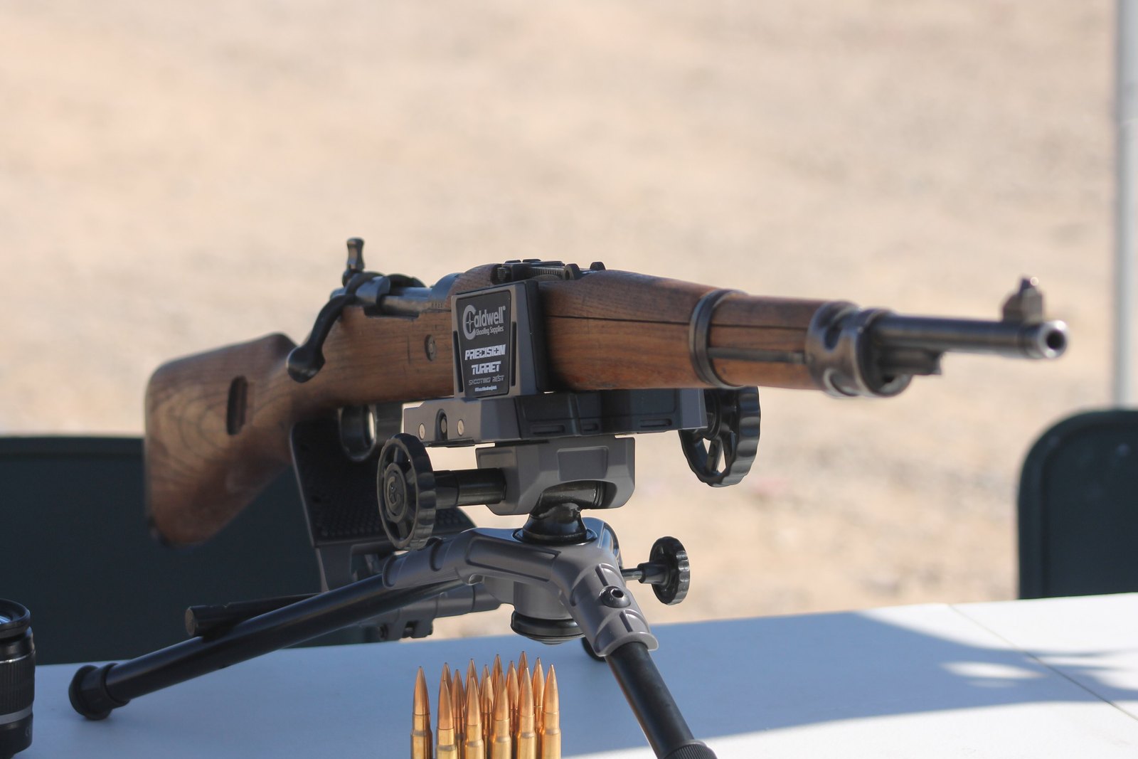 Yugoslavian Zastava M48 Mauser rifle on a shooting rest at an outdoor range with 8mm Mauser cartridges on the bench