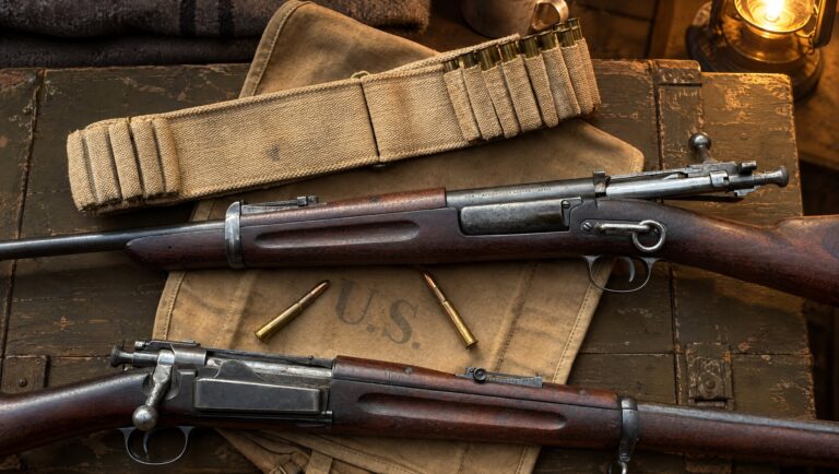 Two loose 30-40 Krag ammo cartridges and a cartridge belt between a Krag carbine and a Krag rifle