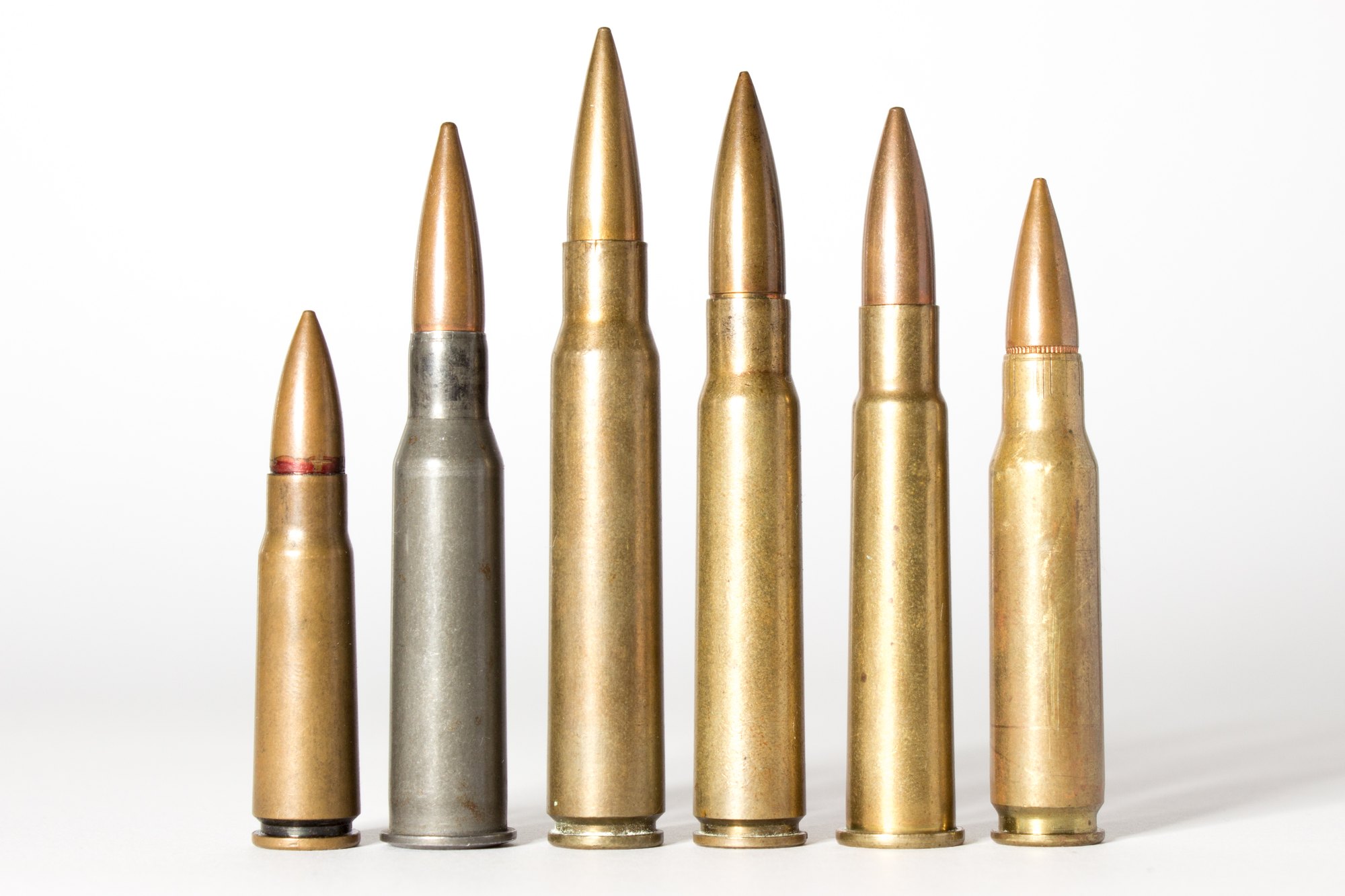 Six rifle cartridges standing in a row, with the rimmed 303 British fifth from the left