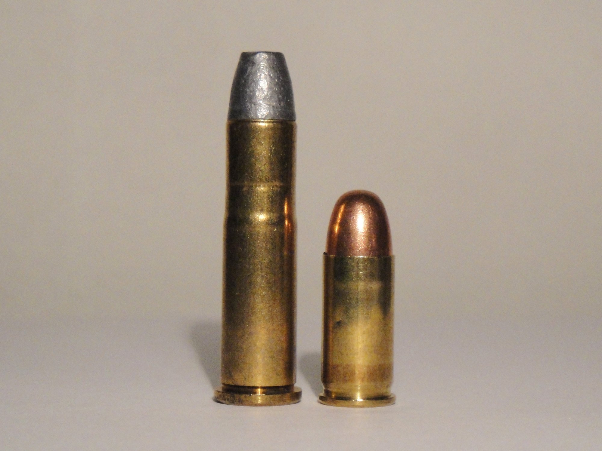 32-20 cartridge with a lead flat-nose bullet standing beside a shorter .32 ACP cartridge