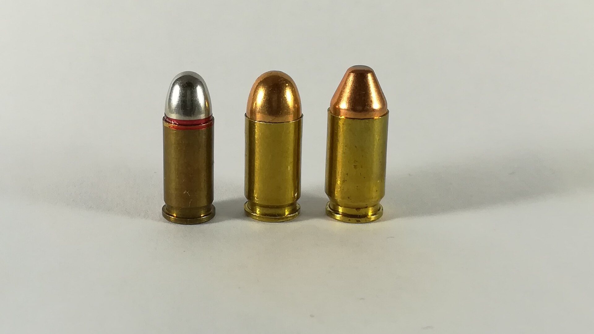 32 ACP, 380 ACP and 9x18 Police cartridges standing in a row on white