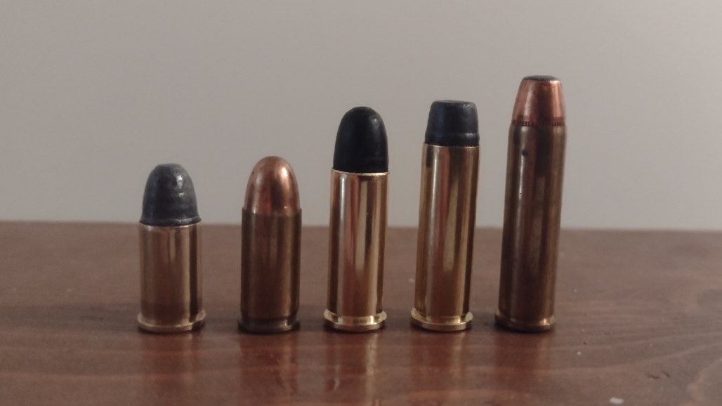 32 Short, 32 ACP, 32 S&W Long, 32 H&R Magnum and 327 Federal Magnum cartridges in a row on a wooden table