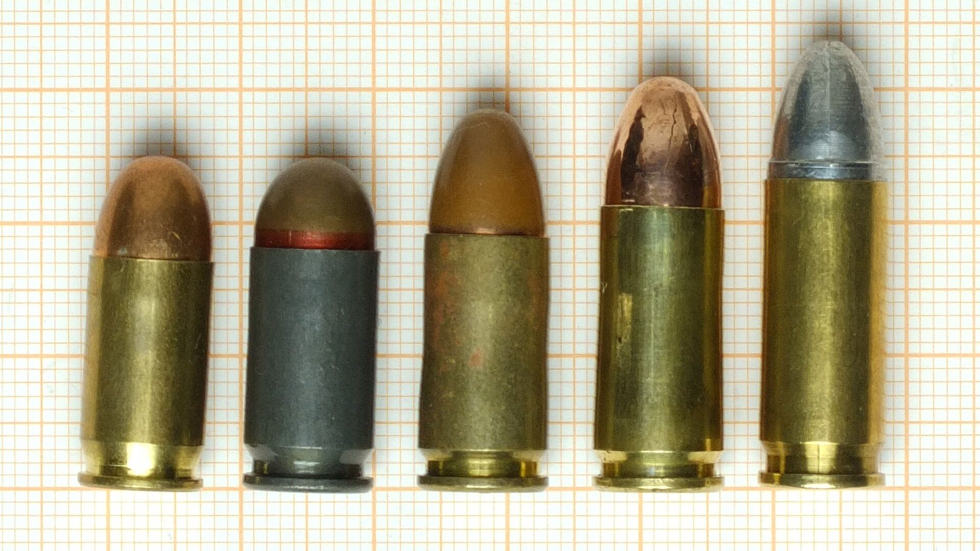 380 ACP, 9x18 Makarov and 9mm Luger cartridges standing on millimeter paper with 9x21 and 9x23