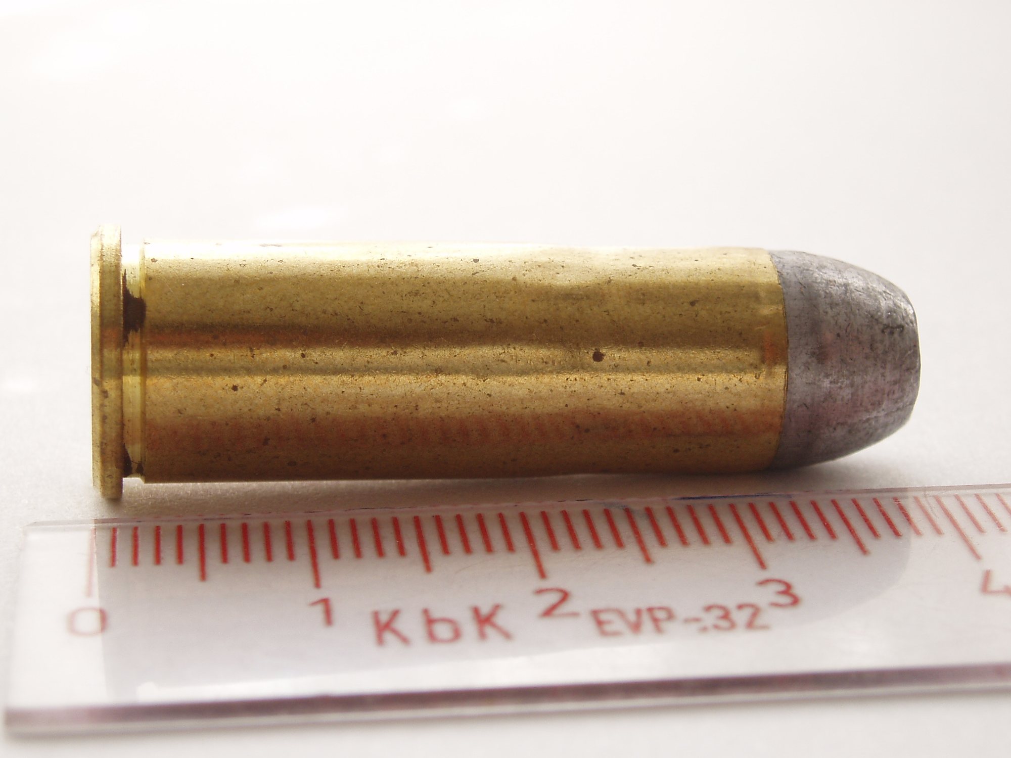 44-40 Winchester cartridge with a lead flat-nose bullet beside a centimeter scale