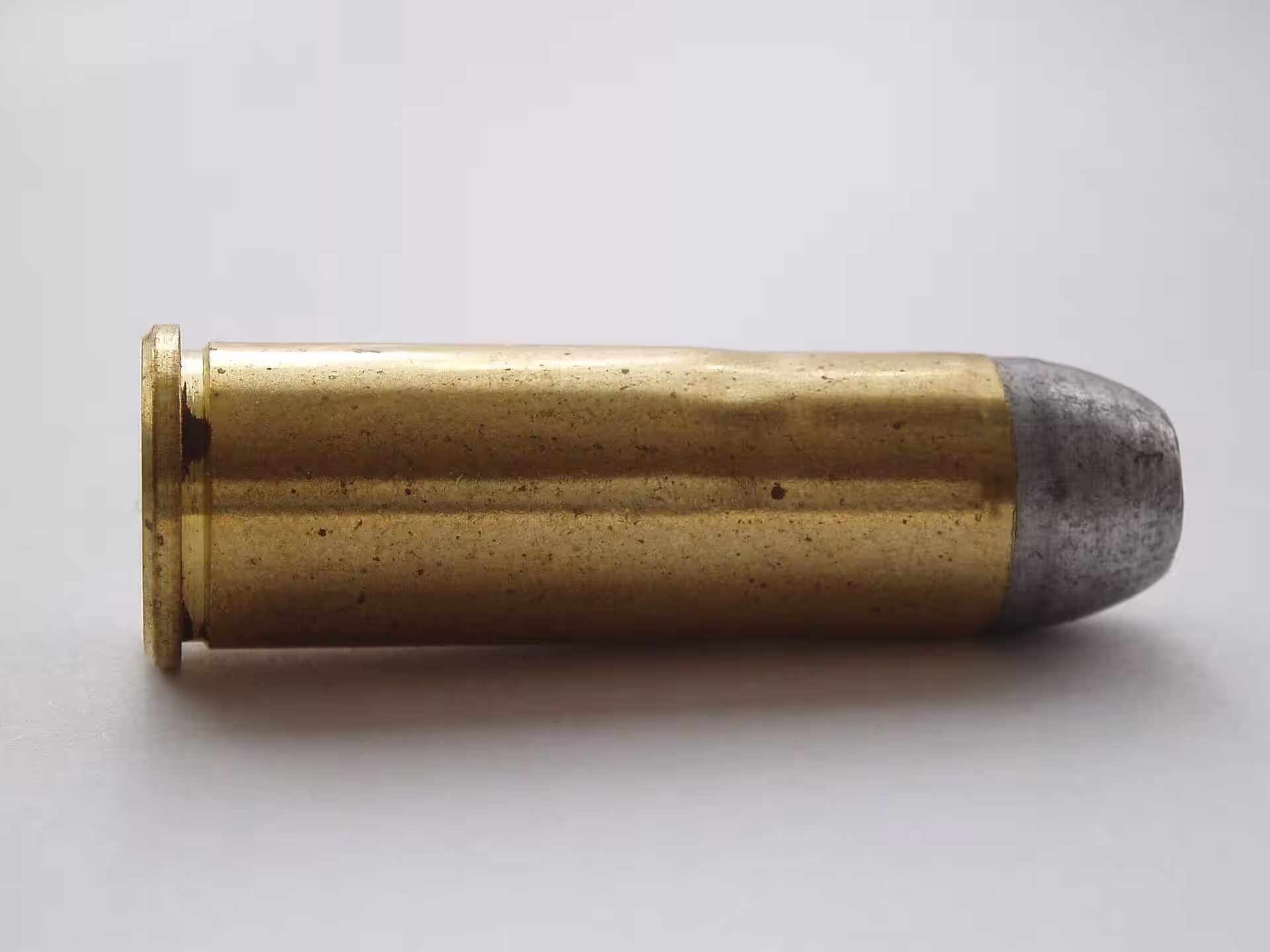 44-40 Winchester cartridge lying on its side on a gray background