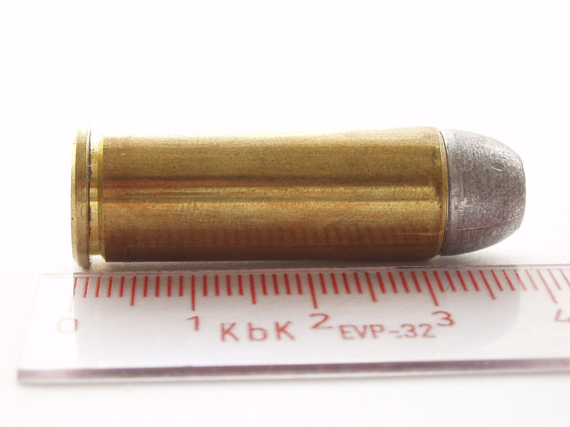 45 Colt cartridge with a lead bullet lying beside a centimeter scale