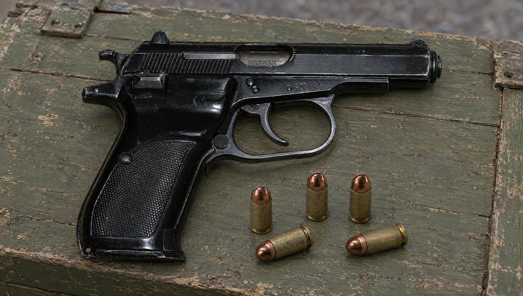 Five 9x18 Makarov ammo cartridges on a green ammunition crate beside a CZ 82 pistol