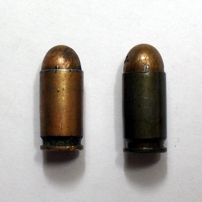 Corroded 1960s 9x18 Makarov round beside a lacquered steel-case round