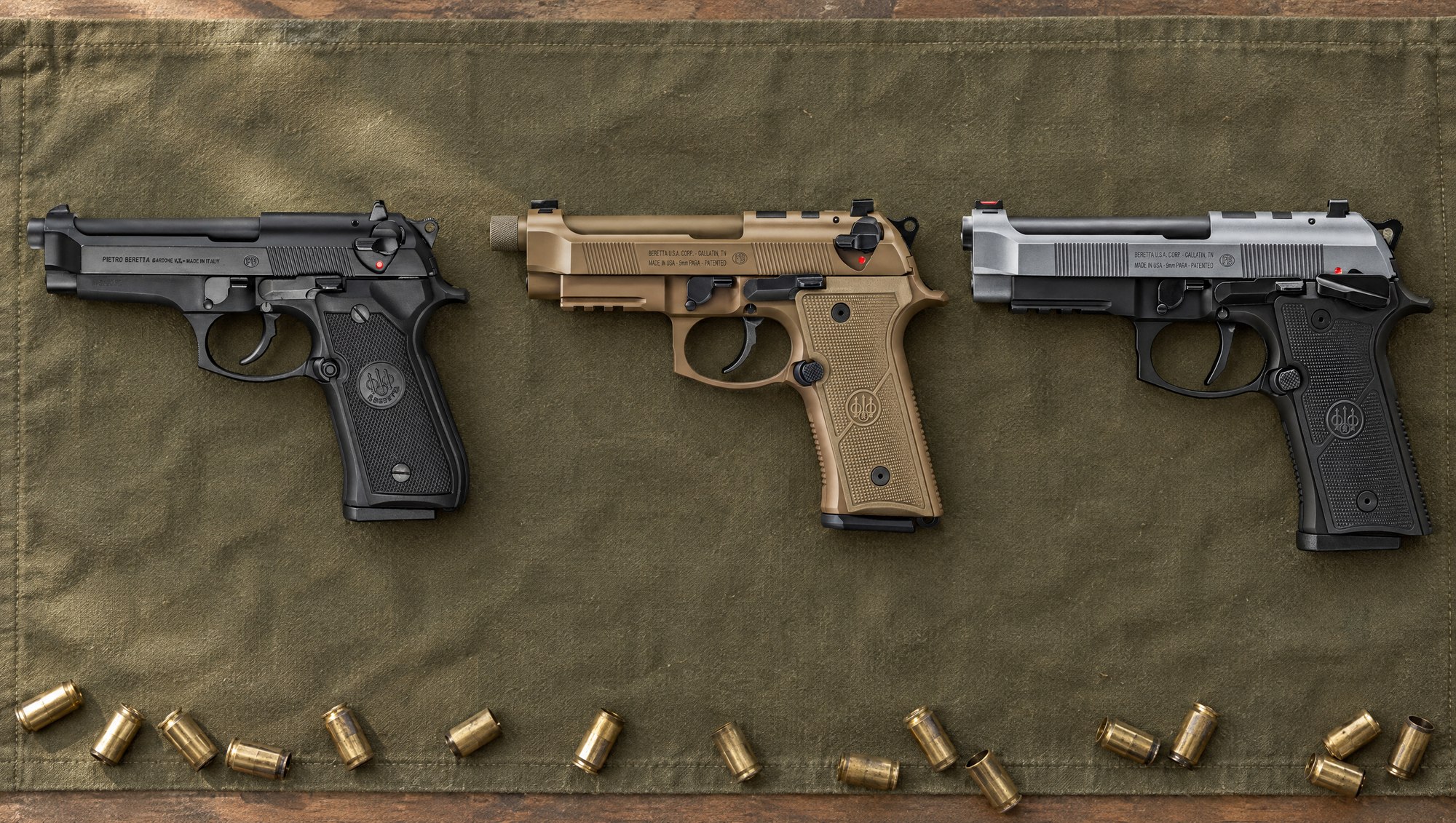 Beretta 92 models compared: a black Beretta 92FS, a Flat Dark Earth Beretta M9A4 and a two-tone Beretta 92XI SAO lying flat on a canvas shooting mat