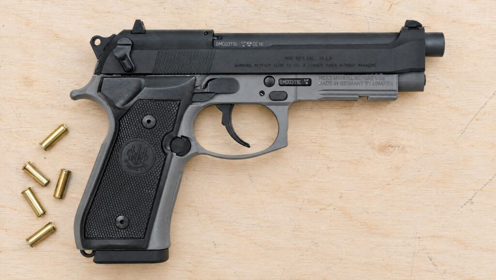 Beretta 92FSR .22 LR in Sniper Gray with accessory rail lying flat on a plywood shooting bench