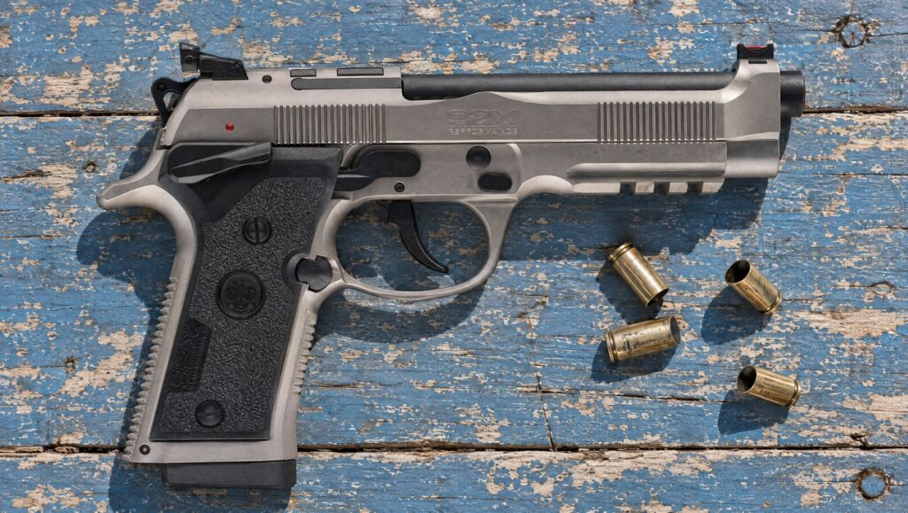 Beretta 92X Performance Carry Optic with Nistan steel frame, frame-mounted safety and rail lying flat on a blue plank range table
