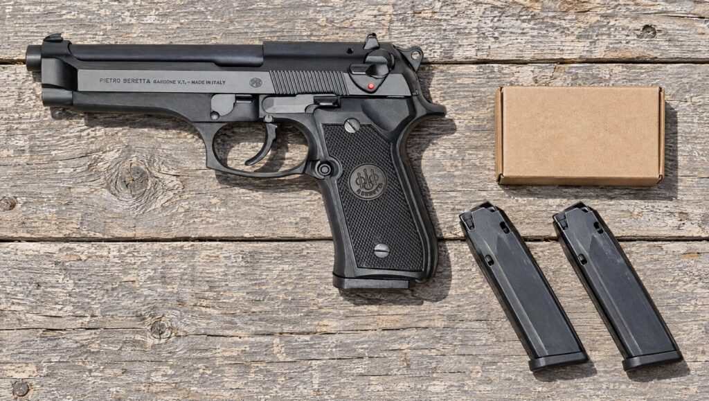 Beretta 92FS on a wooden range bench with two spare magazines and a box of 9mm ammunition