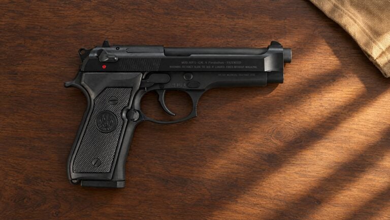 Beretta 92FS right side lying flat on a walnut table, showing the MOD. 92FS slide legend and a frame with no accessory rail
