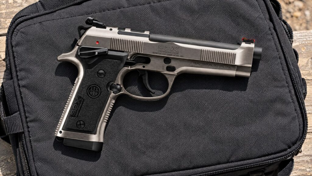 Beretta 92X Performance Defensive 9mm pistol in Nistan finish lying flat on a dark gray range bag in midday sun, right side showing the frame safety and the smooth dust cover with no rail