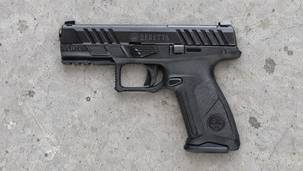 Beretta APX A1 Full Size 9mm pistol lying flat on a gray concrete range bench, left side showing the BERETTA slide marking and the APX frame mark