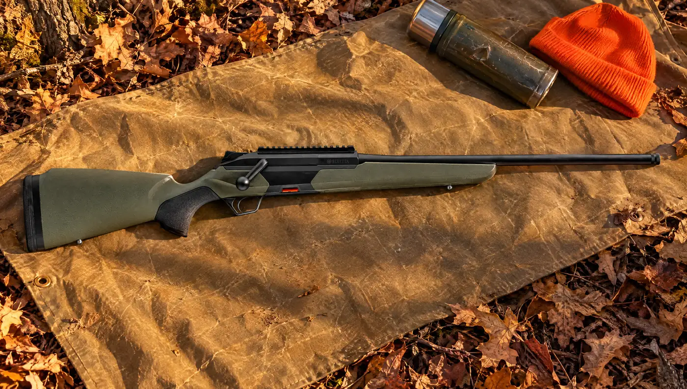 Beretta BRX1 Green straight-pull rifle with olive polymer stock and Picatinny rail lying on a tan canvas tarp over oak leaves beside a steel thermos and a blaze orange cap