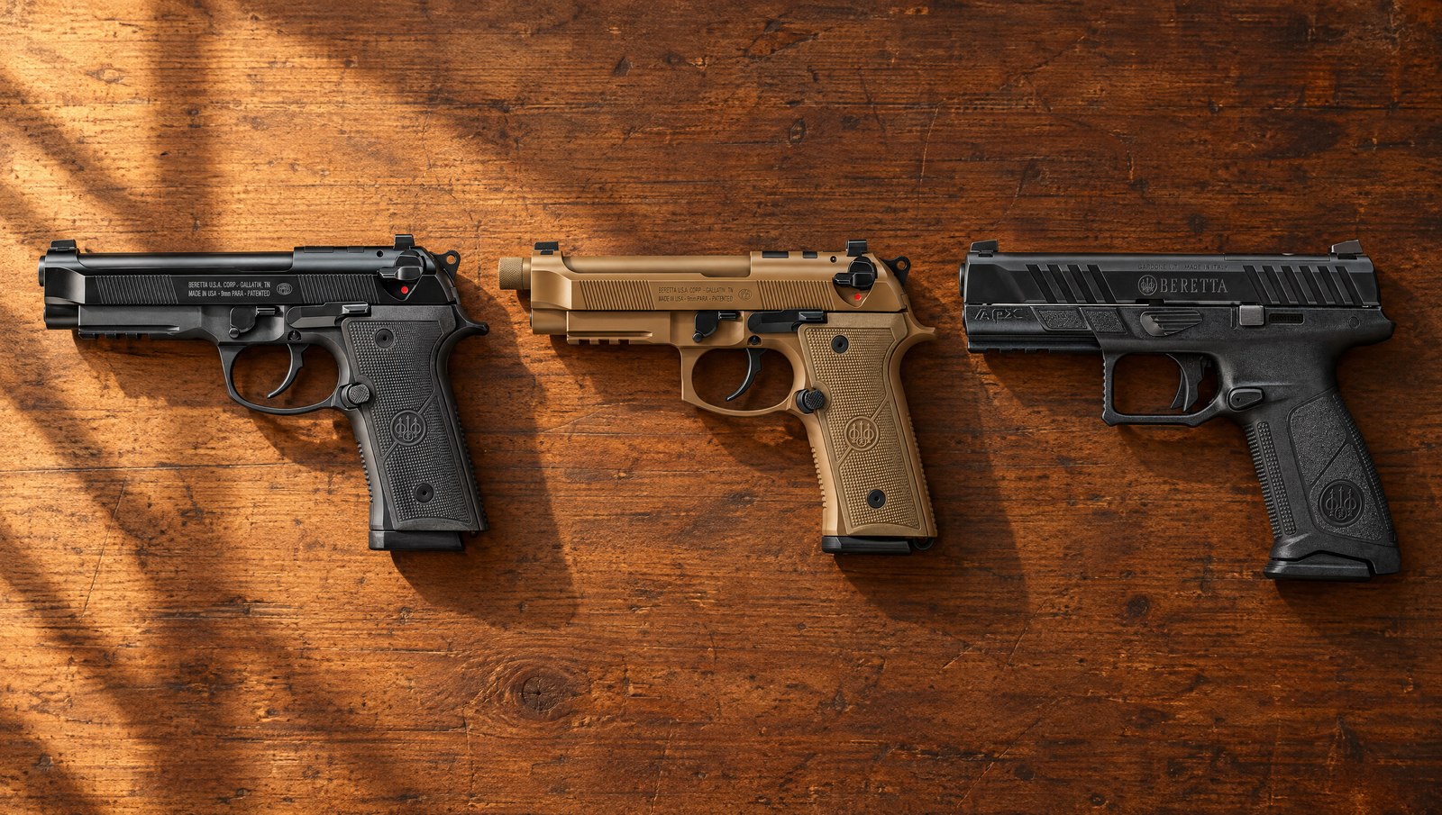 Beretta 92X RDO Full Size, M9A4 in Flat Dark Earth and APX A1 Full Size pistols lying flat on a walnut counter in evening sun, left sides showing