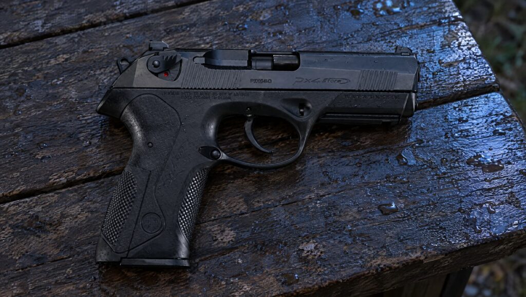 Beretta PX4 Storm full-size pistol lying flat on a rain-darkened wooden picnic table at dusk, right side showing the Px4 Storm slide logo, hammer and safety lever