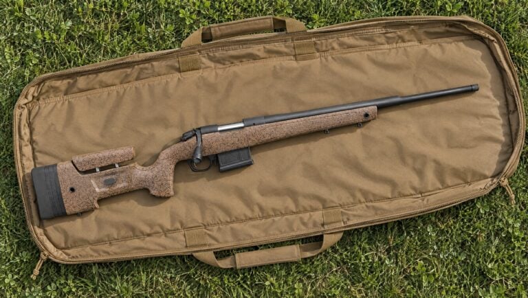 Bergara B-14 HMR with brown speckled stock and black barrel lying flat on an open tan rifle drag bag on grass, right side up