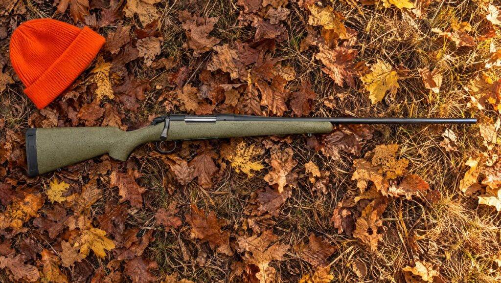 Bergara B-14 Hunter with green speckled synthetic stock and slim Cerakote barrel lying flat on fallen oak leaves