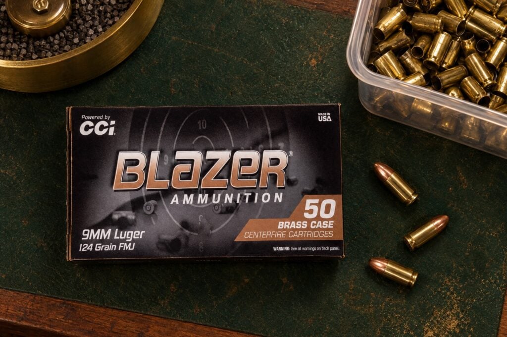 Box of CCI Blazer Brass 9mm Luger 124 grain FMJ on a reloading bench beside a bin of fired brass cases