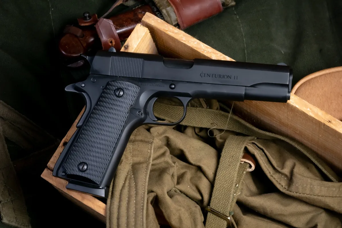 Black Century Arms Centurion 11 GI pattern 1911 resting on a wooden crate with olive drab canvas gear, Century Arms photo