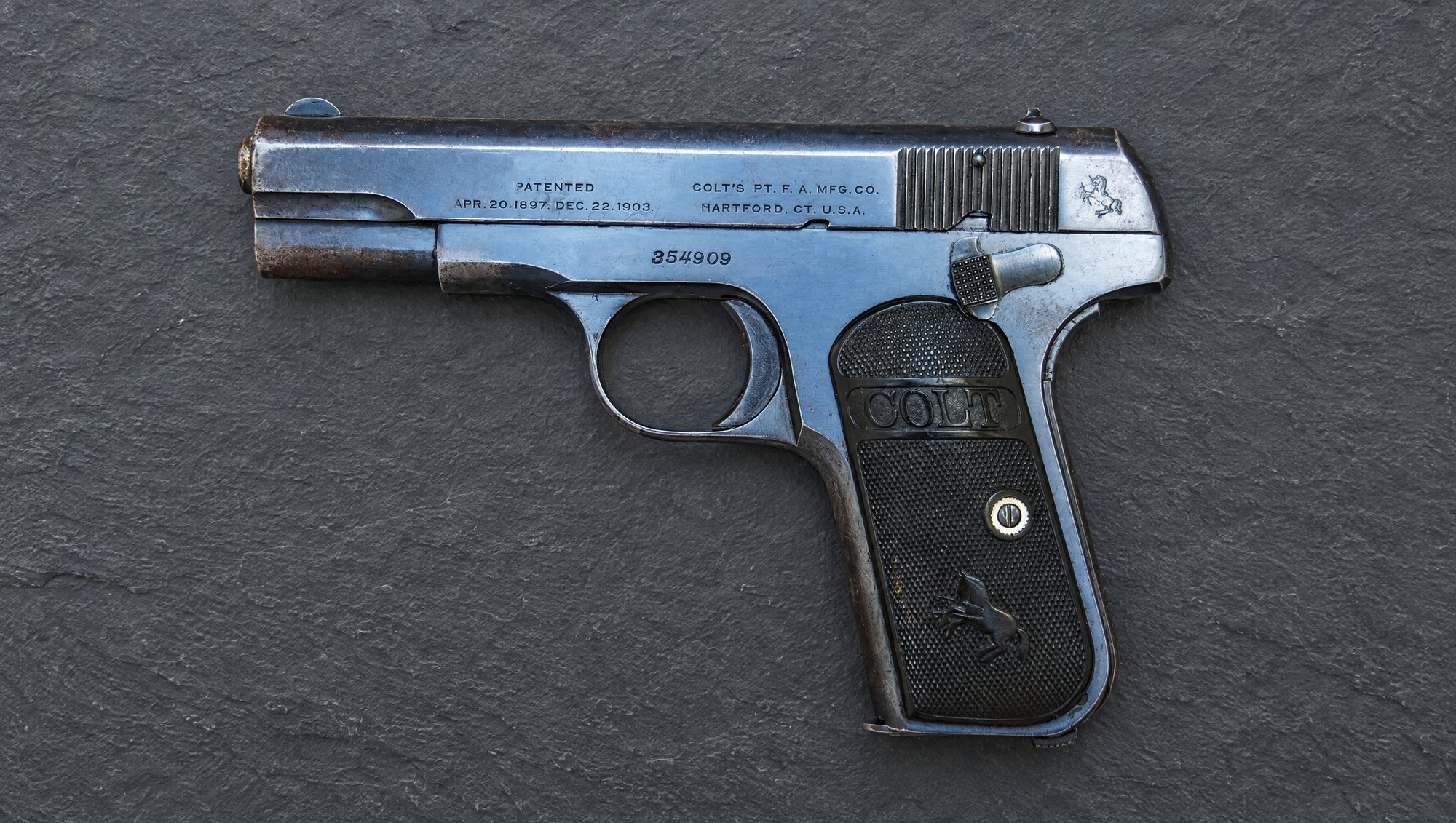 Blued Colt Model 1903 Pocket Hammerless pistol in 32 ACP on dark slate