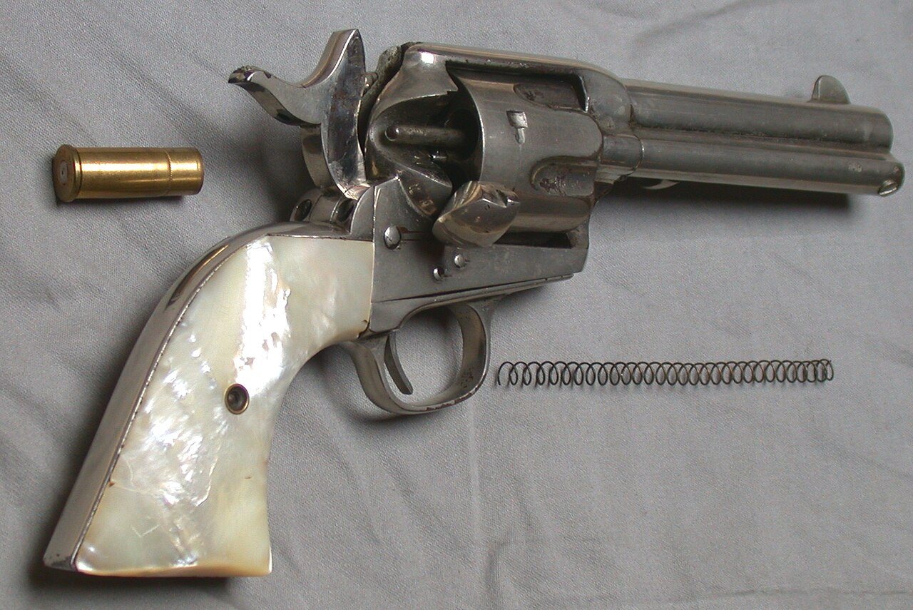 Nickel Colt Single Action Army revolver with the loading gate open and an empty case beside it