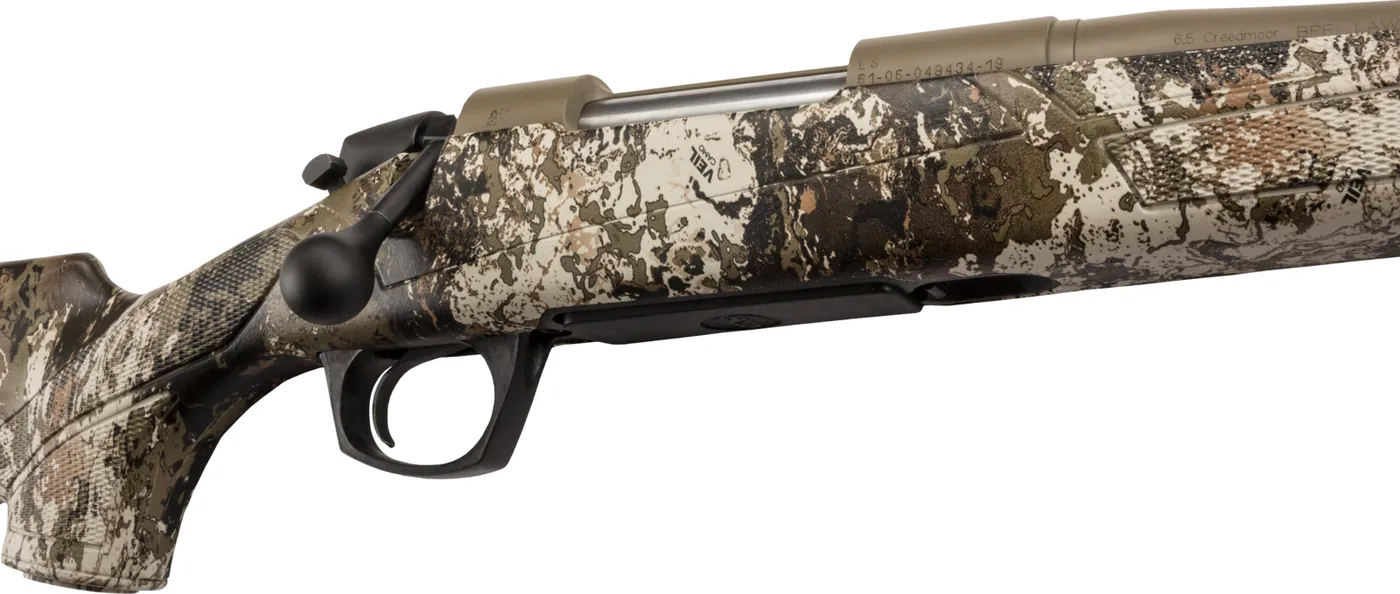 Close-up of a CVA Cascade action in Flat Dark Earth Cerakote with a Veil Wideland camo stock showing the bolt handle, trigger guard and 6.5 Creedmoor barrel marking, CVA photo