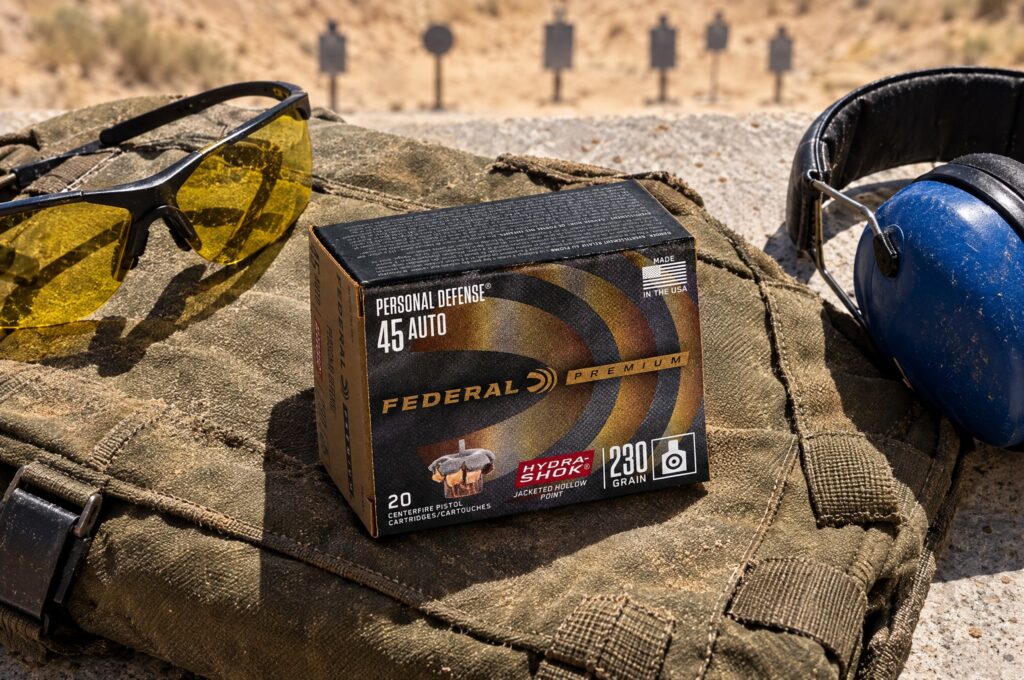 Box of Federal Personal Defense Hydra-Shok 45 Auto 230 gr on a canvas range bag beside shooting glasses and ear muffs
