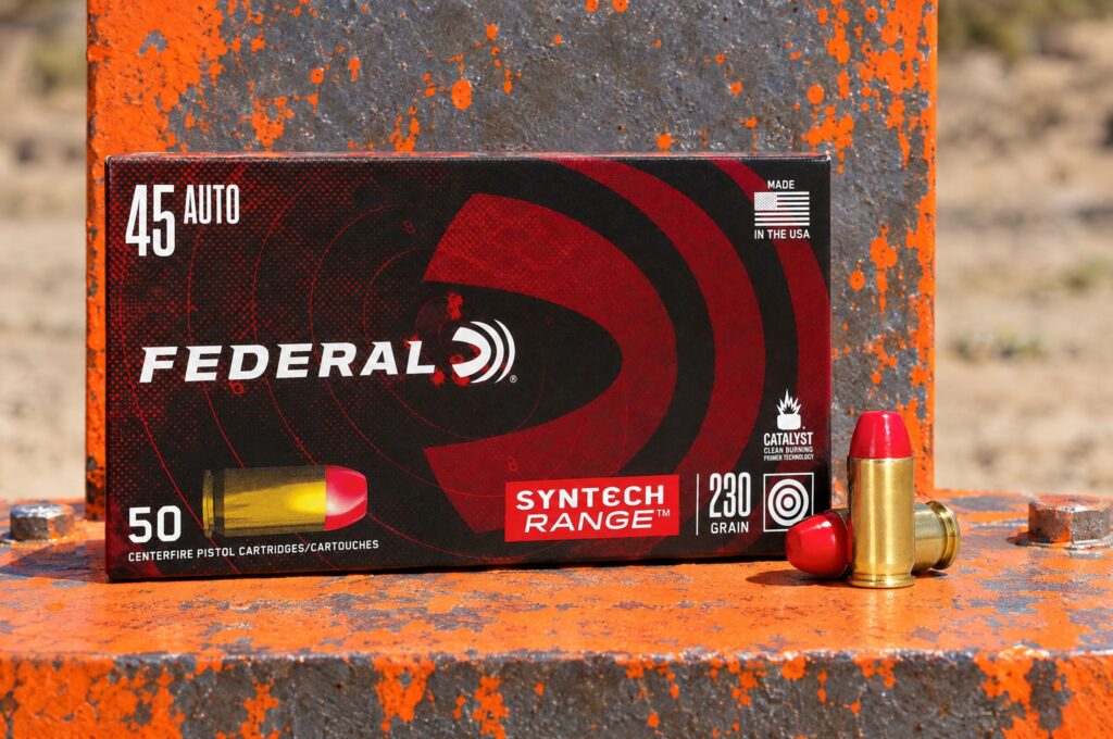 Federal Syntech Range 45 Auto 230 grain box and red polymer jacketed cartridges at the base of a painted steel target