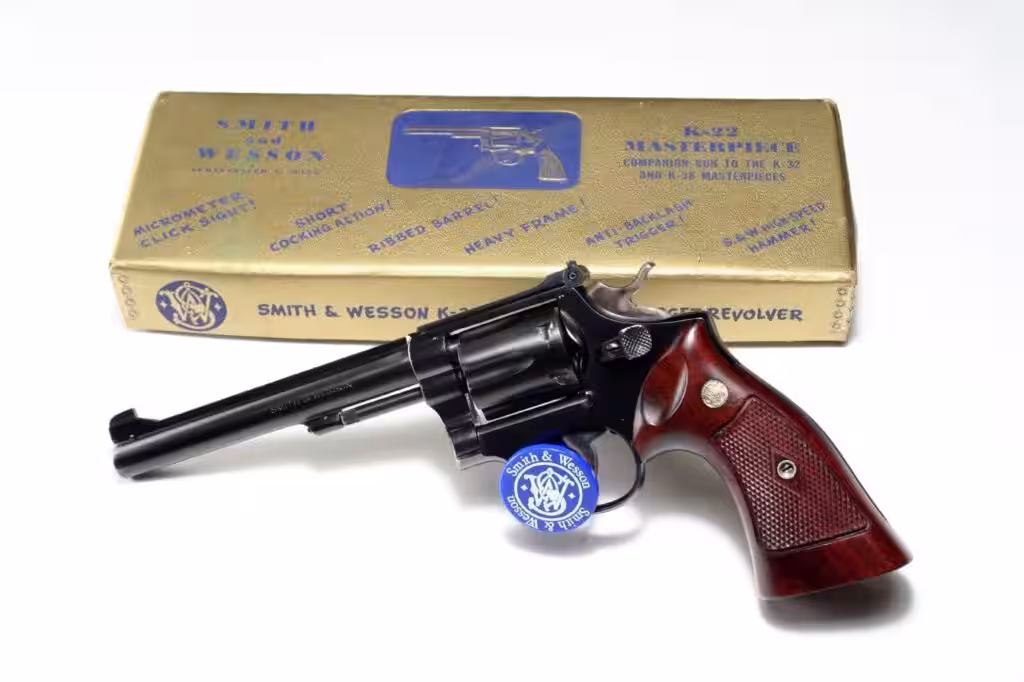 Smith and Wesson K-22 revolver in front of its original box, photographed on a white background