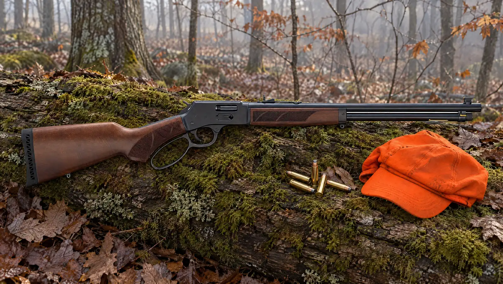 Henry H12 Provider lever action rifle with a blued steel receiver and checkered walnut pistol grip stock lying on a mossy log in an autumn forest beside .44 Magnum cartridges and a blaze orange cap