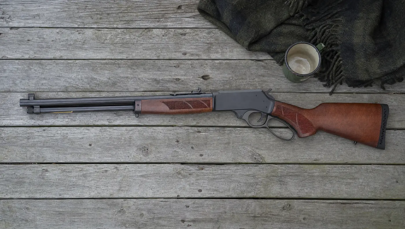 Henry H9 Provider lever action rifle lying on a weathered cabin porch beside a wool blanket and an enamel mug