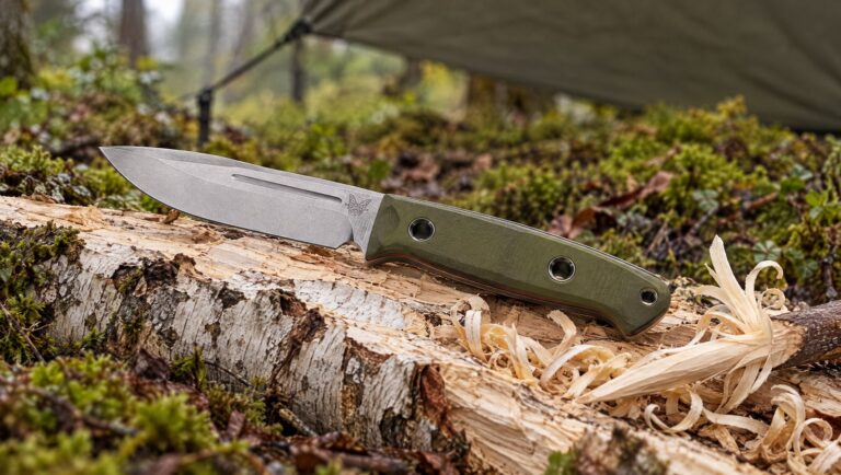 Benchmade 163-1 Bushcrafter knife on a split birch log with wood shavings at a forest camp
