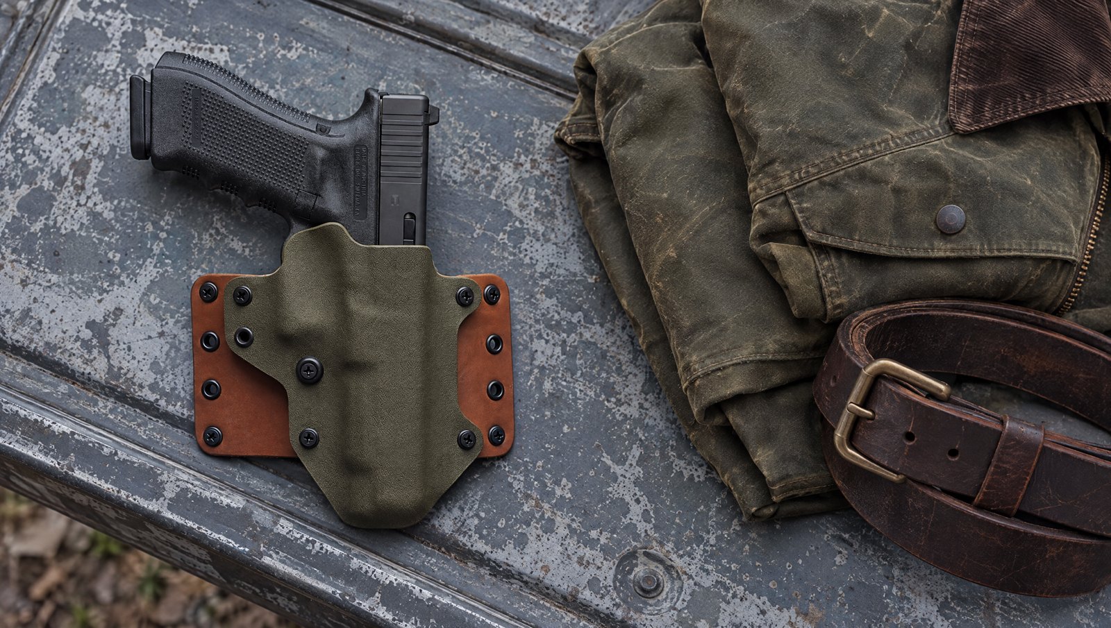 Black Point Tactical Leather Wing OWB holster with a Glock on a pickup tailgate beside a field jacket and leather gun belt