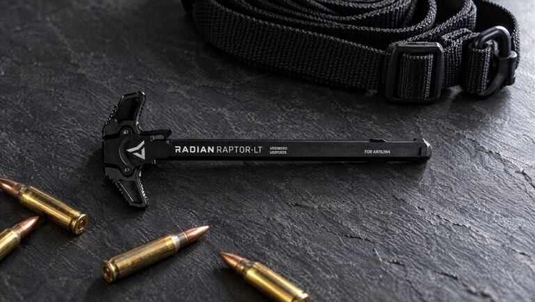 Radian Raptor-LT ambidextrous AR-15 charging handle on a slate surface with a sling and 5.56 cartridges