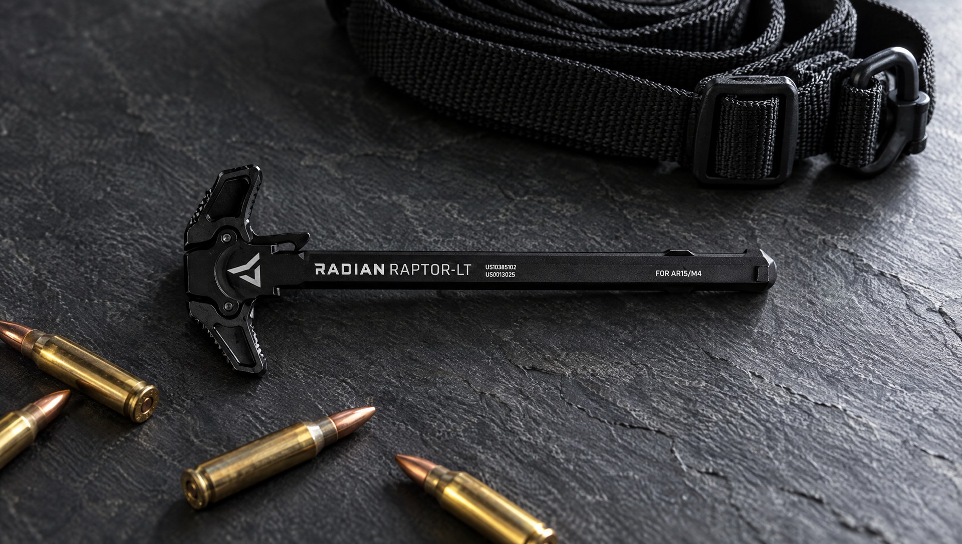Radian Raptor-LT ambidextrous AR-15 charging handle on a slate surface with a sling and 5.56 cartridges