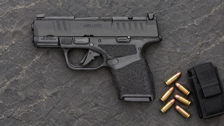 Springfield Armory Hellcat OSP 9mm micro-compact pistol lying flat on a slate surface beside 9mm cartridges