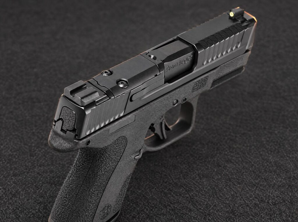 Close-up of the Smith and Wesson M&P Shield X optic cut cover plate, rear sight and slide serrations