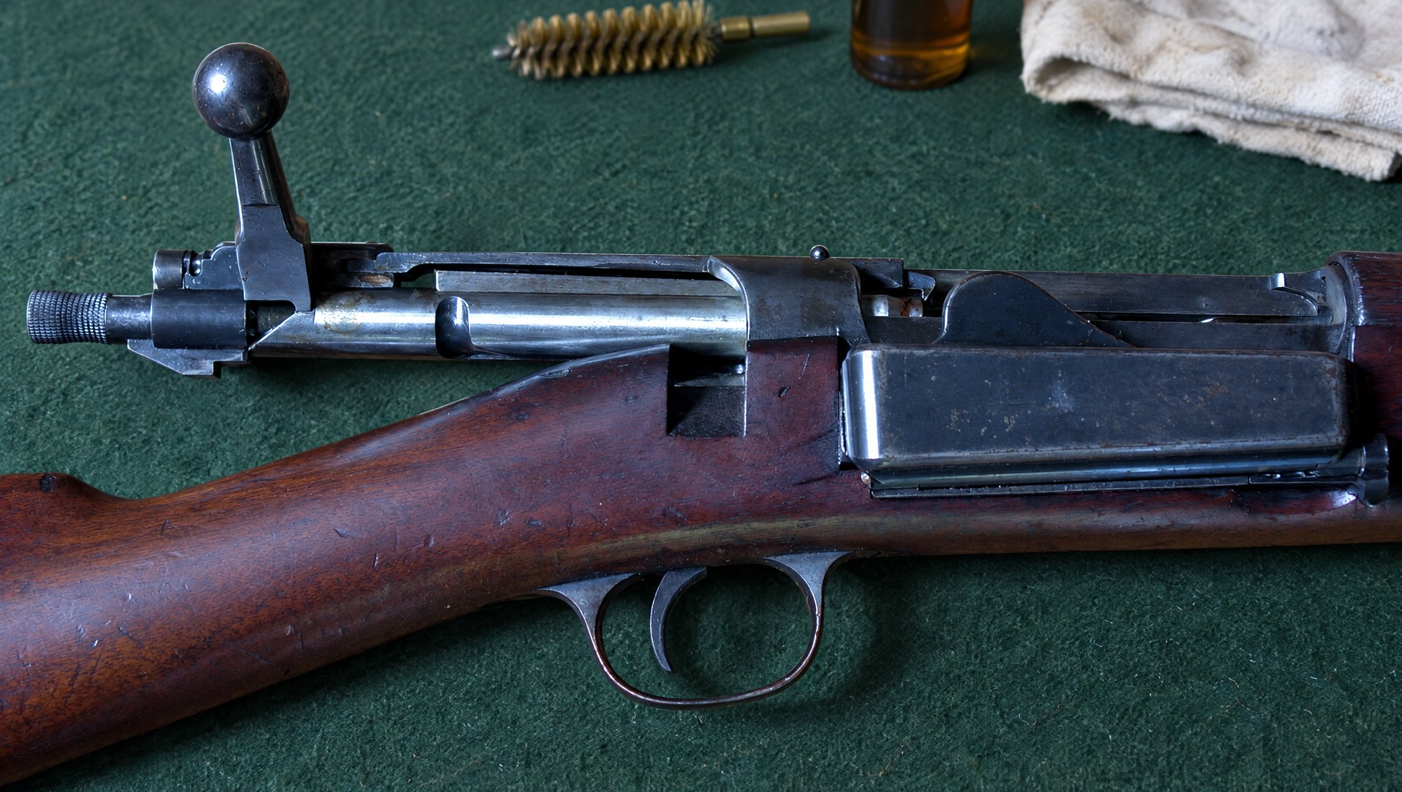 Krag-Jorgensen rifle action with the bolt open and side magazine box, on a gunsmith bench