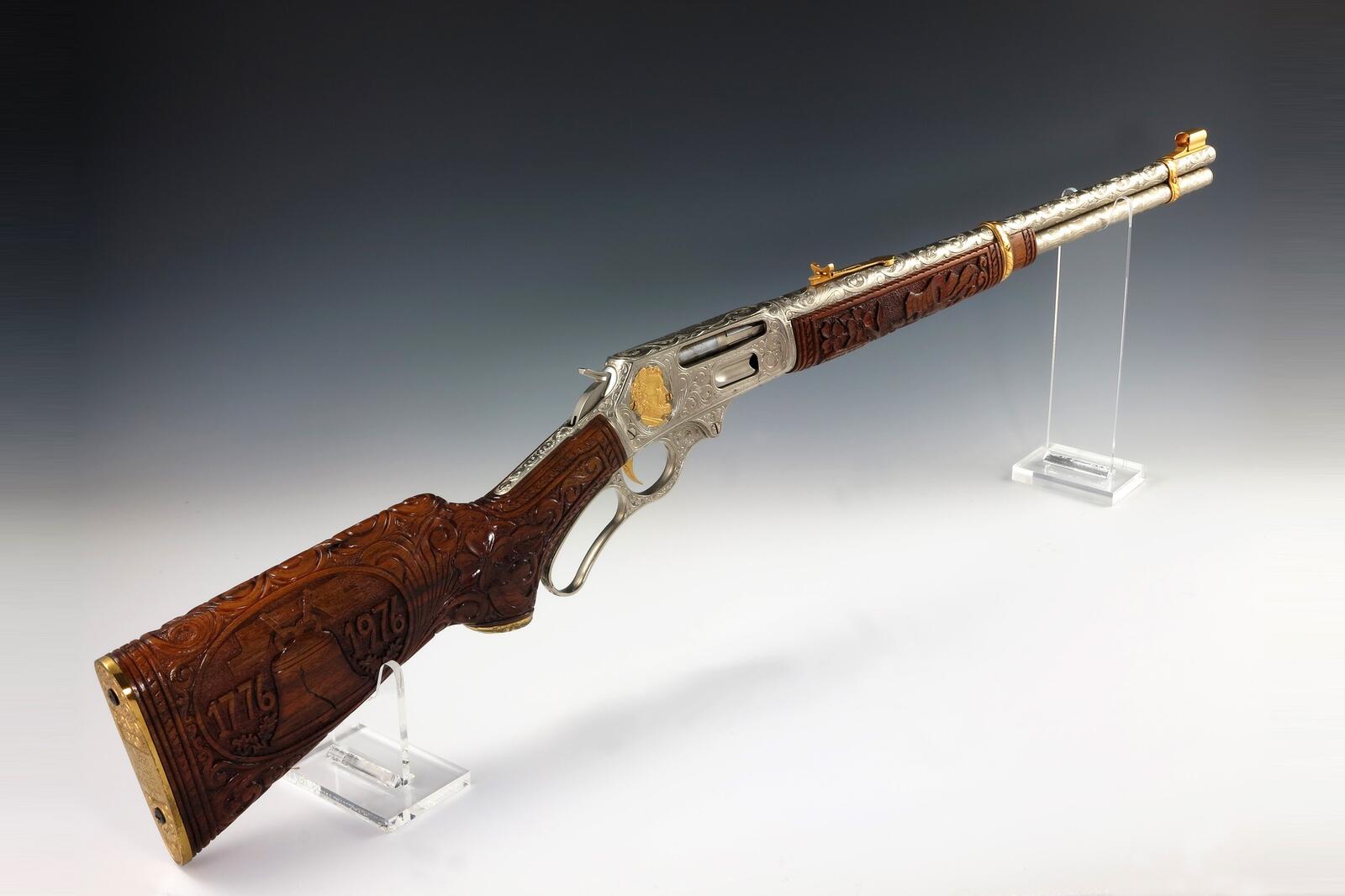 An engraved Marlin Model 336 lever-action rifle with a carved walnut stock dated 1776 and 1976, on clear stands at the Gerald R. Ford Presidential Museum