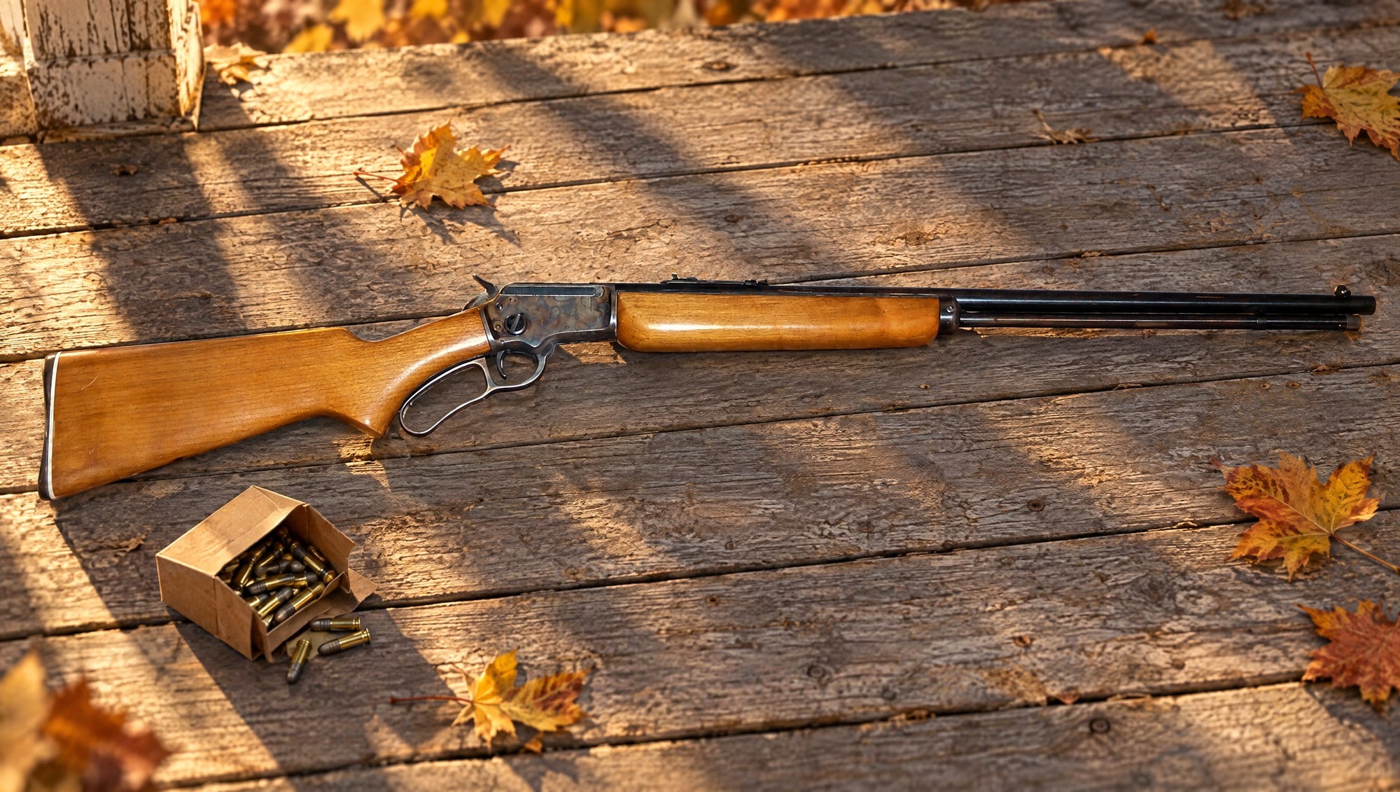 Early Marlin 39A lever-action .22 rifle with walnut pistol-grip stock lying on weathered porch boards in autumn light